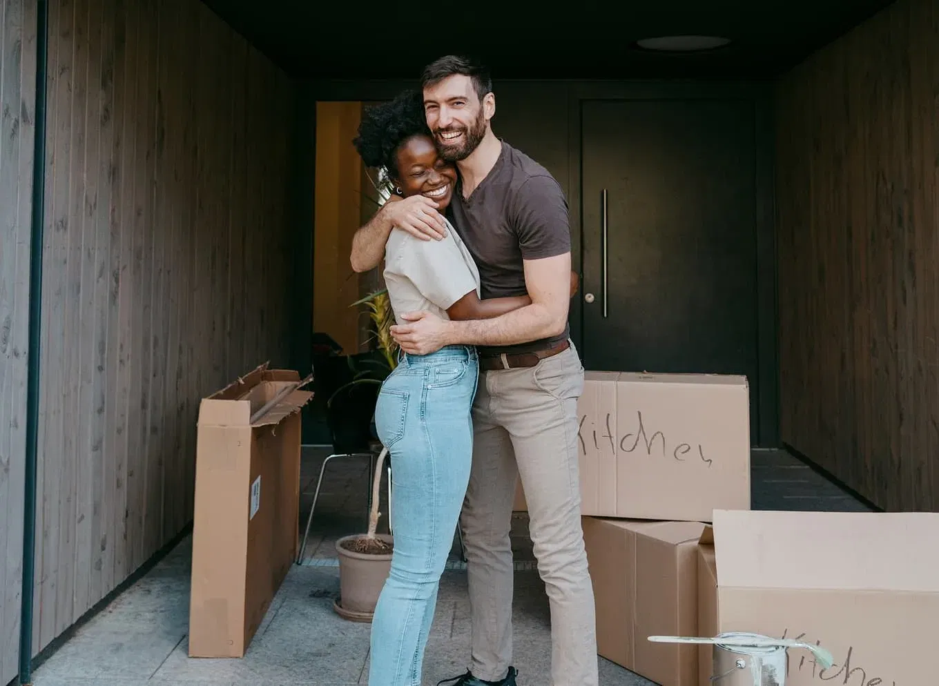 Couple with moving boxes in front of new home
